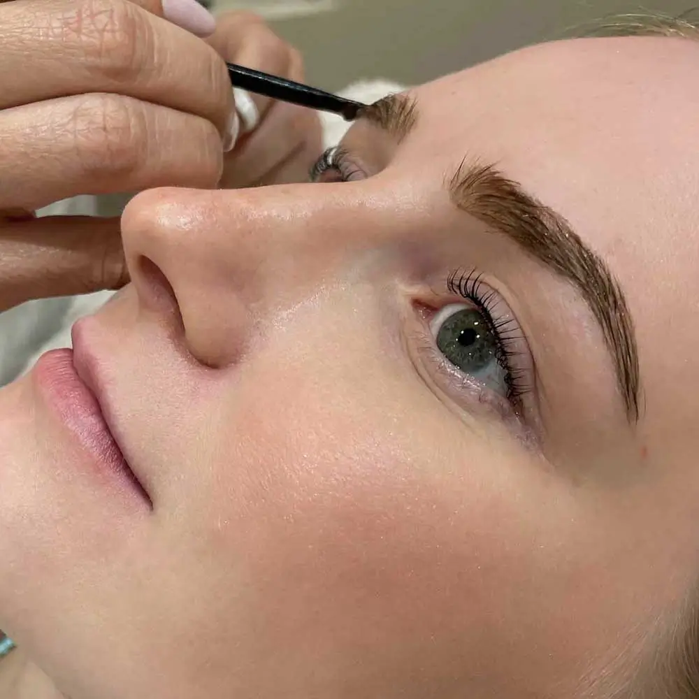 Técnico aplicando un tinte de cejas a una mujer