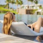 Chica tomando sol en una silla flotando en la piscina.